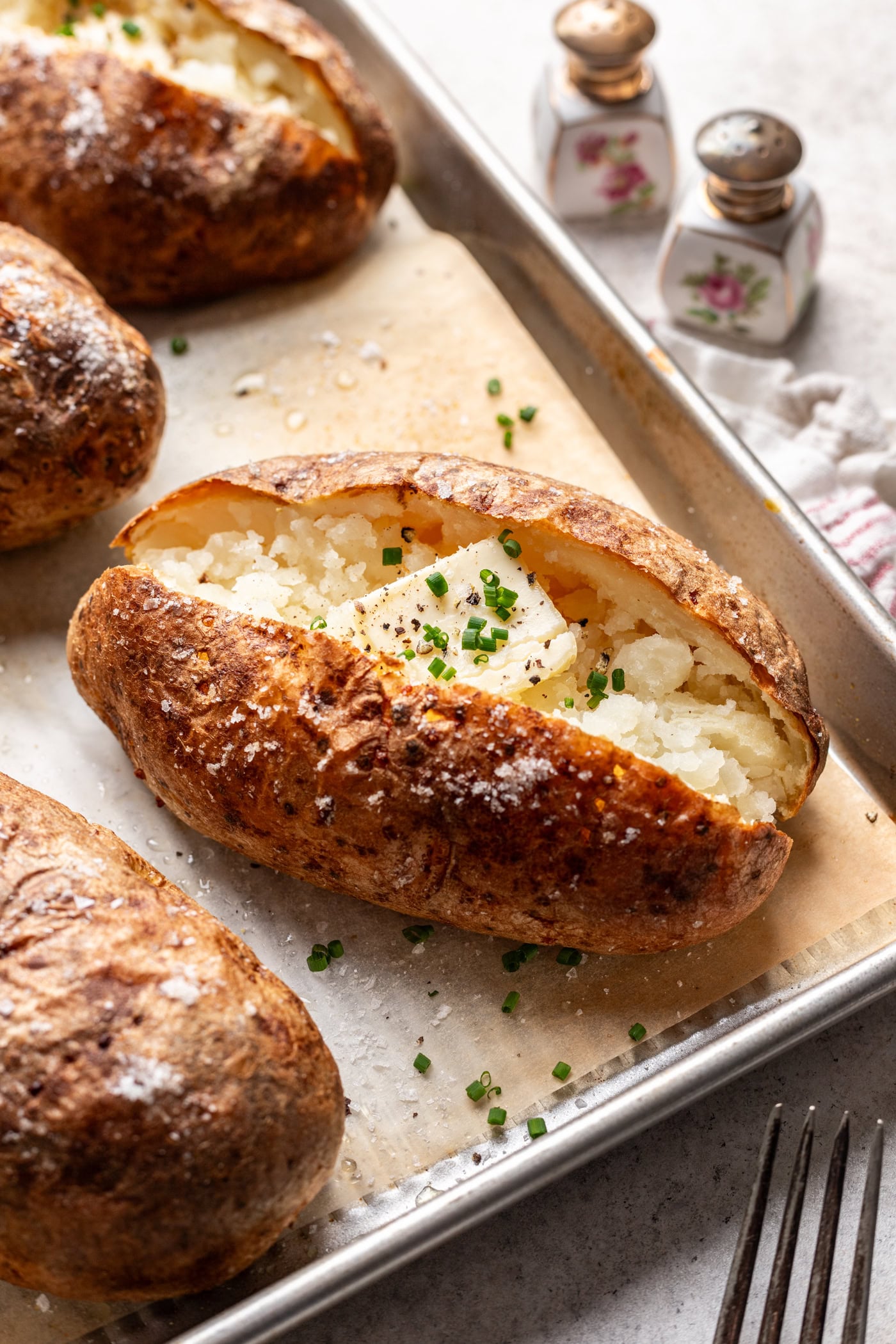 baked potato on a sheet pan with a pat of butter and chives
